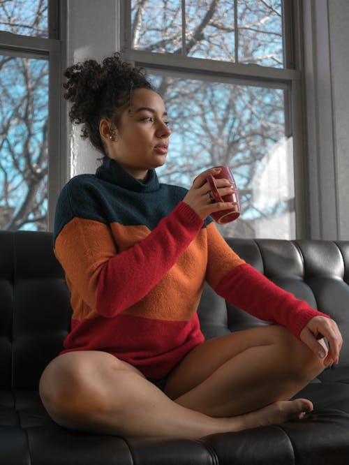 Free Woman in a Sweater Sitting on Black Couch Stock Photo