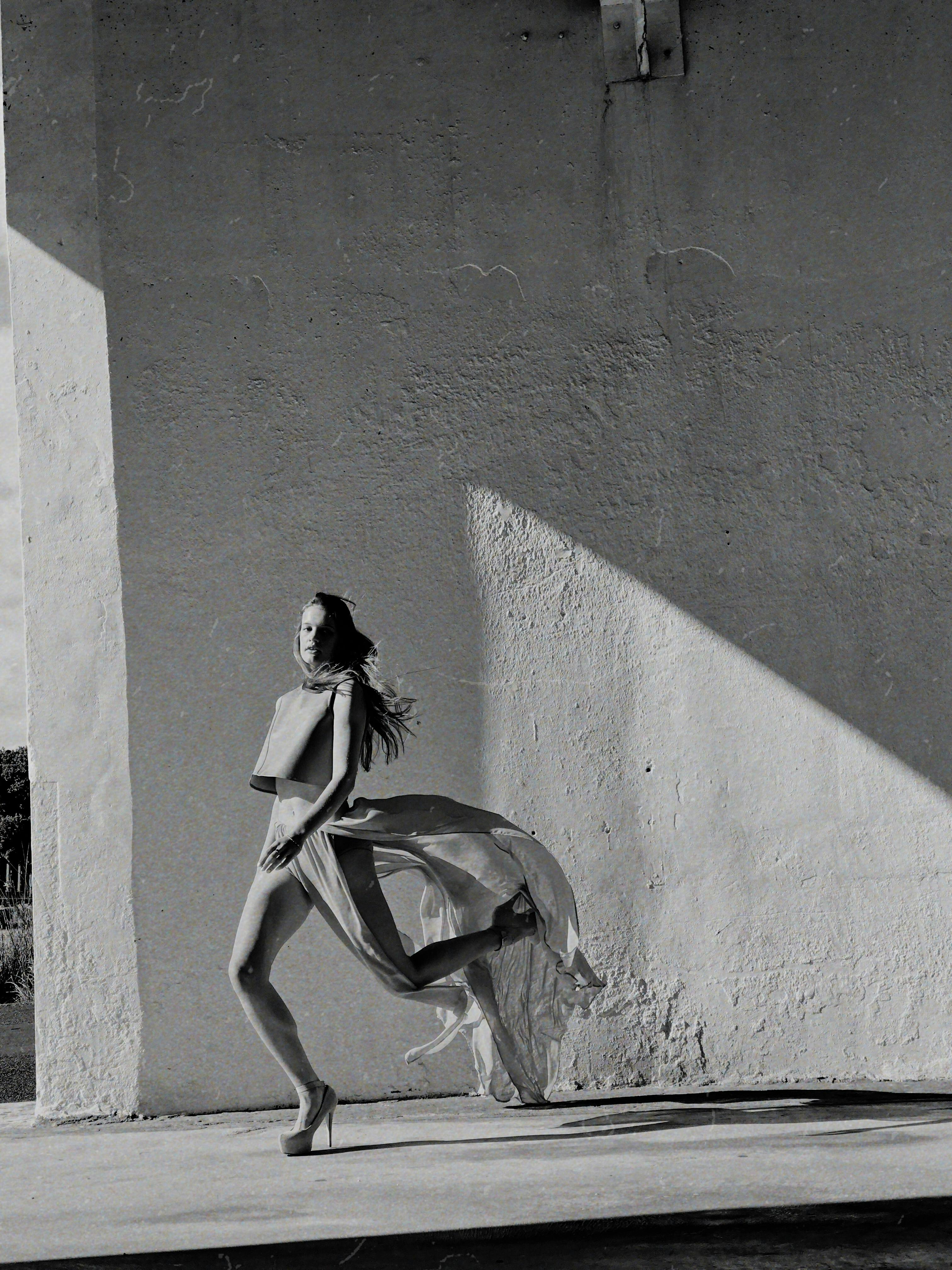 在这张优雅的黑白时尚照片中，模特身着飘逸的连衣裙，姿态灵动