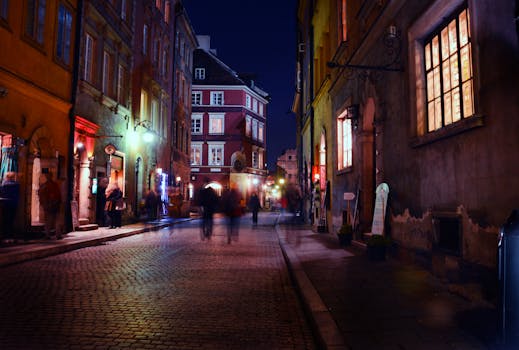 Charming night scene in a historic European city with blurred figures strolling under warm streetlights.