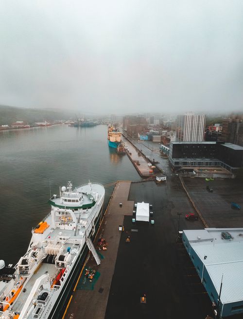 Free From above of big ships on river in port near buildings under cloudy sky on foggy day in town Stock Photo