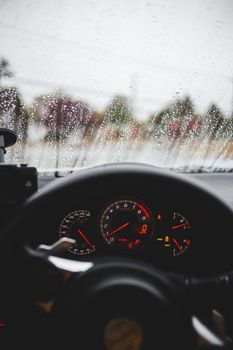 从车内看雨天，视线聚焦在速度表和挡风玻璃的雨滴上