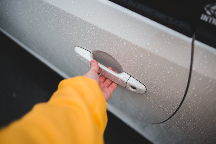 Crop Person Touching Handle Of Car Door In Rain