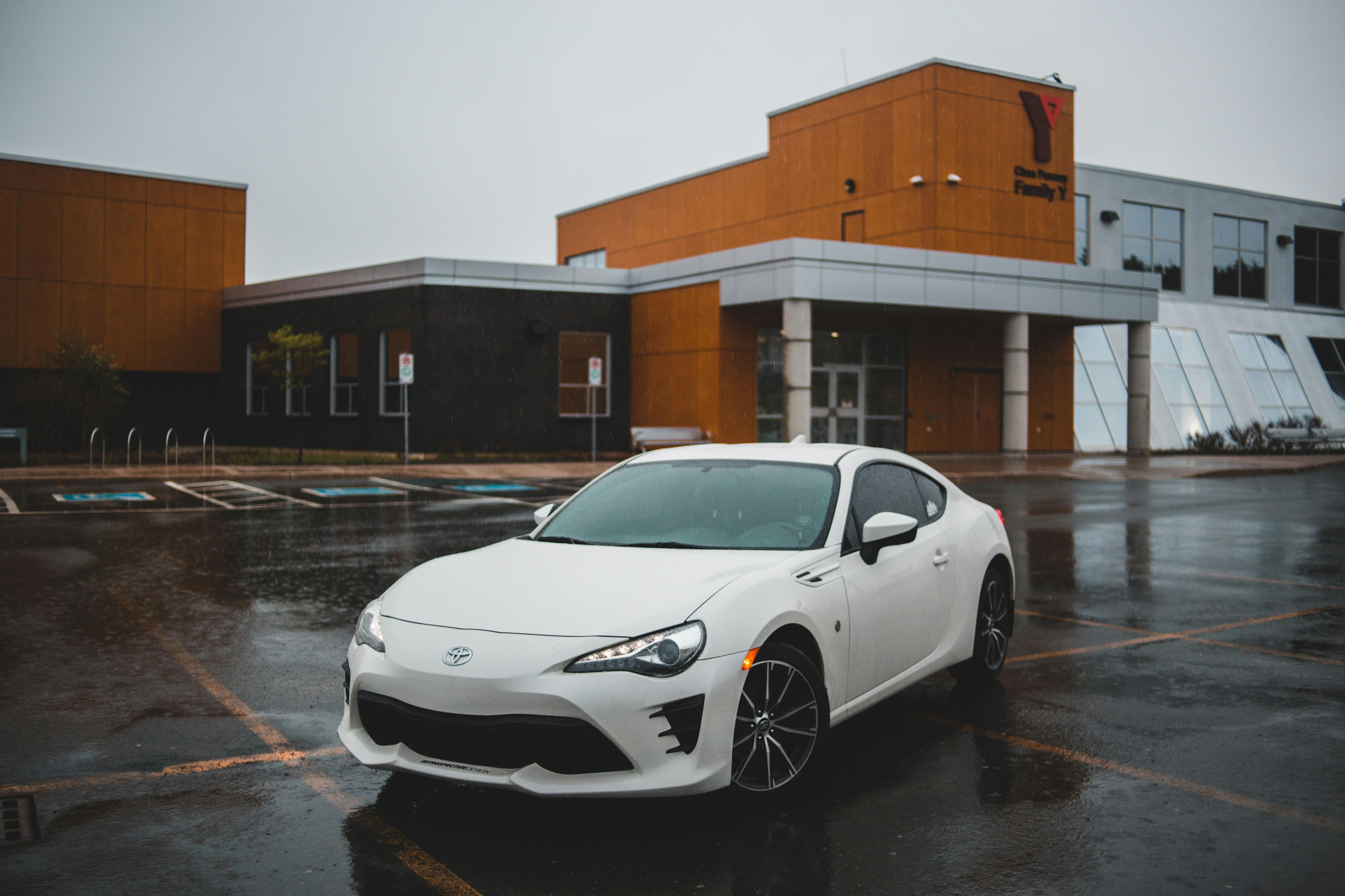 modern car on wet road behind building facade