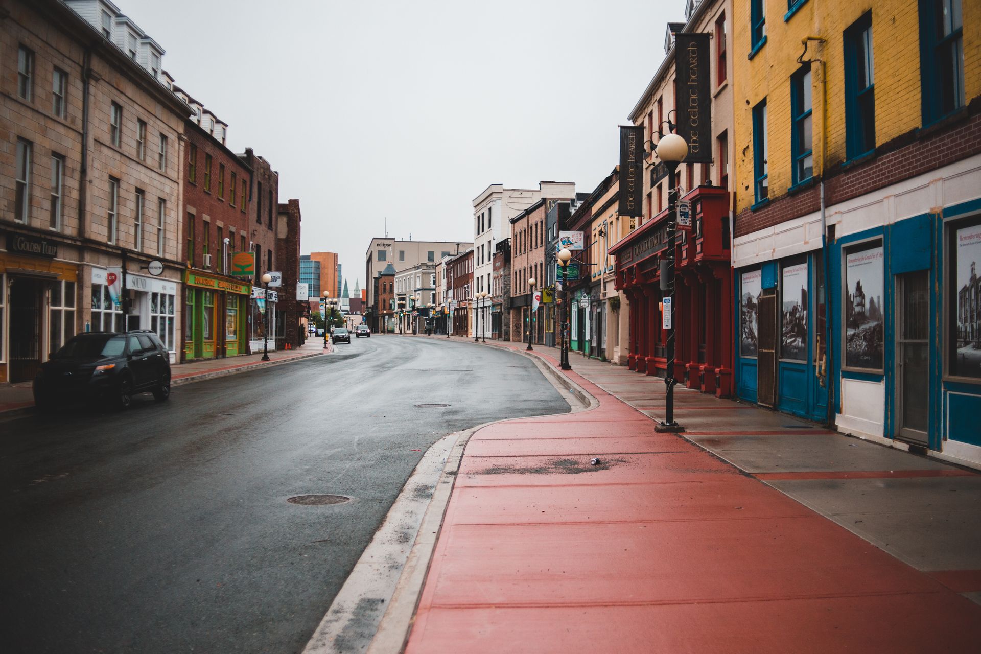 An empty city street lined with closed storefronts under overcast skies