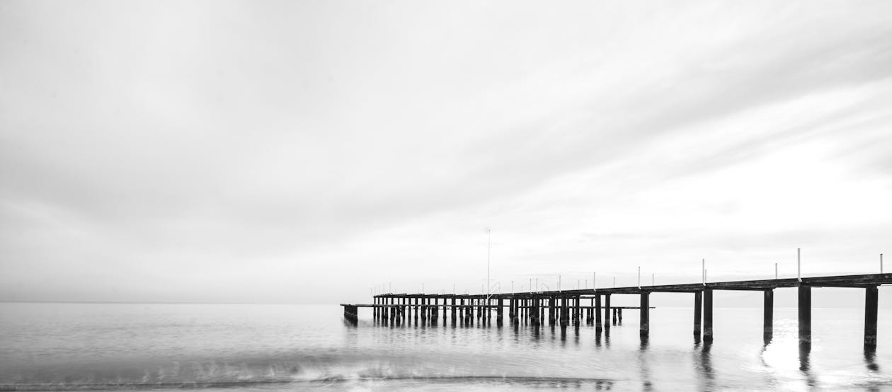 Black Wooden Bridge Under White Sky