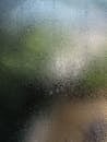 特写图中，潮湿的玻璃板上水滴形成了模糊的背景效果