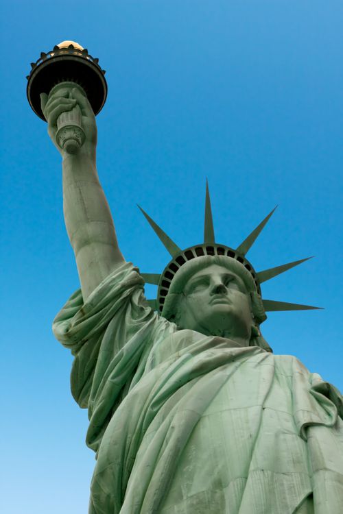 Free Low-angle view of the Statue of Liberty, symbolizing freedom, with a clear blue sky backdrop. Stock Photo