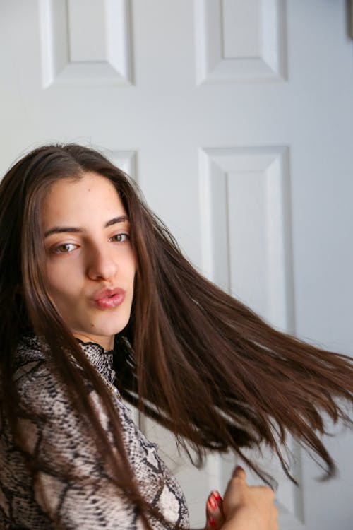 Free Side view of content young female with long brown hair making duck face and looking at camera Stock Photo