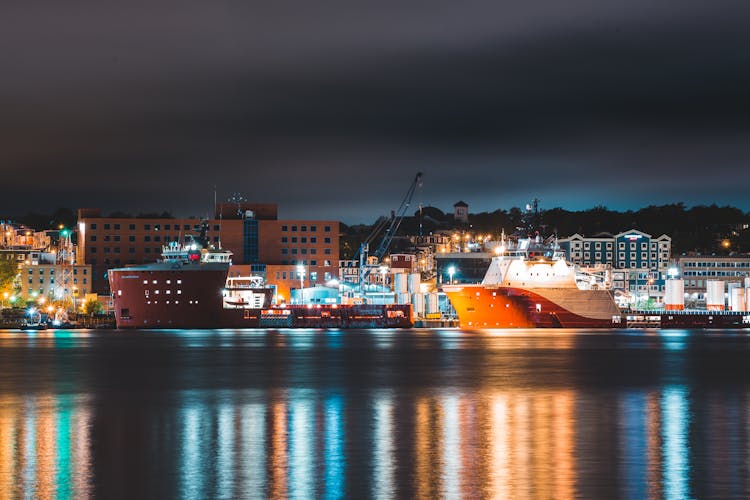 Ships Moored In Port Of Modern City At Night