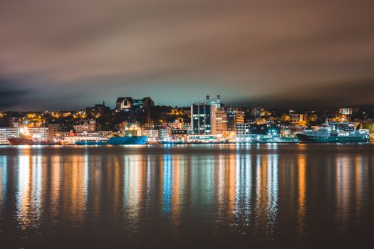 圣约翰多云夜空中，沿海城市彩色的灯光照亮了海面