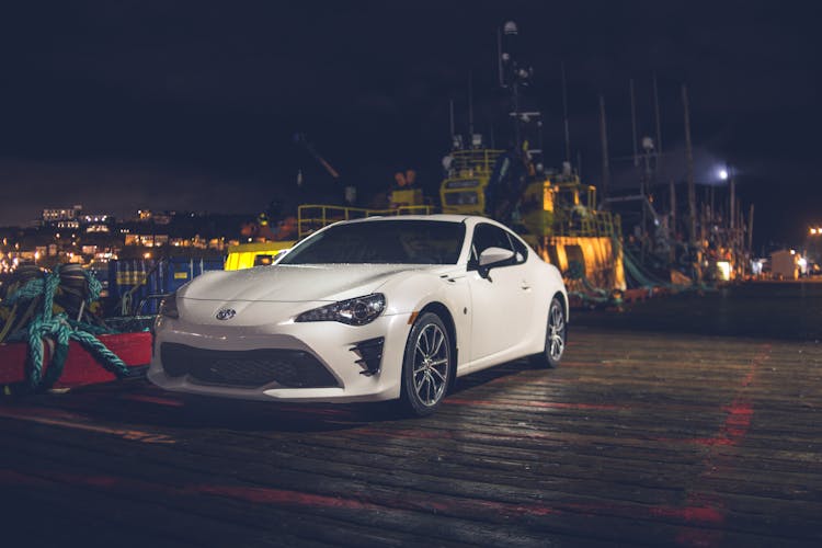 Contemporary Car Parked On Embankment Near Port At Night