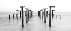 这张有趣的长曝光黑白照片中，一个生锈的码头延伸至海洋