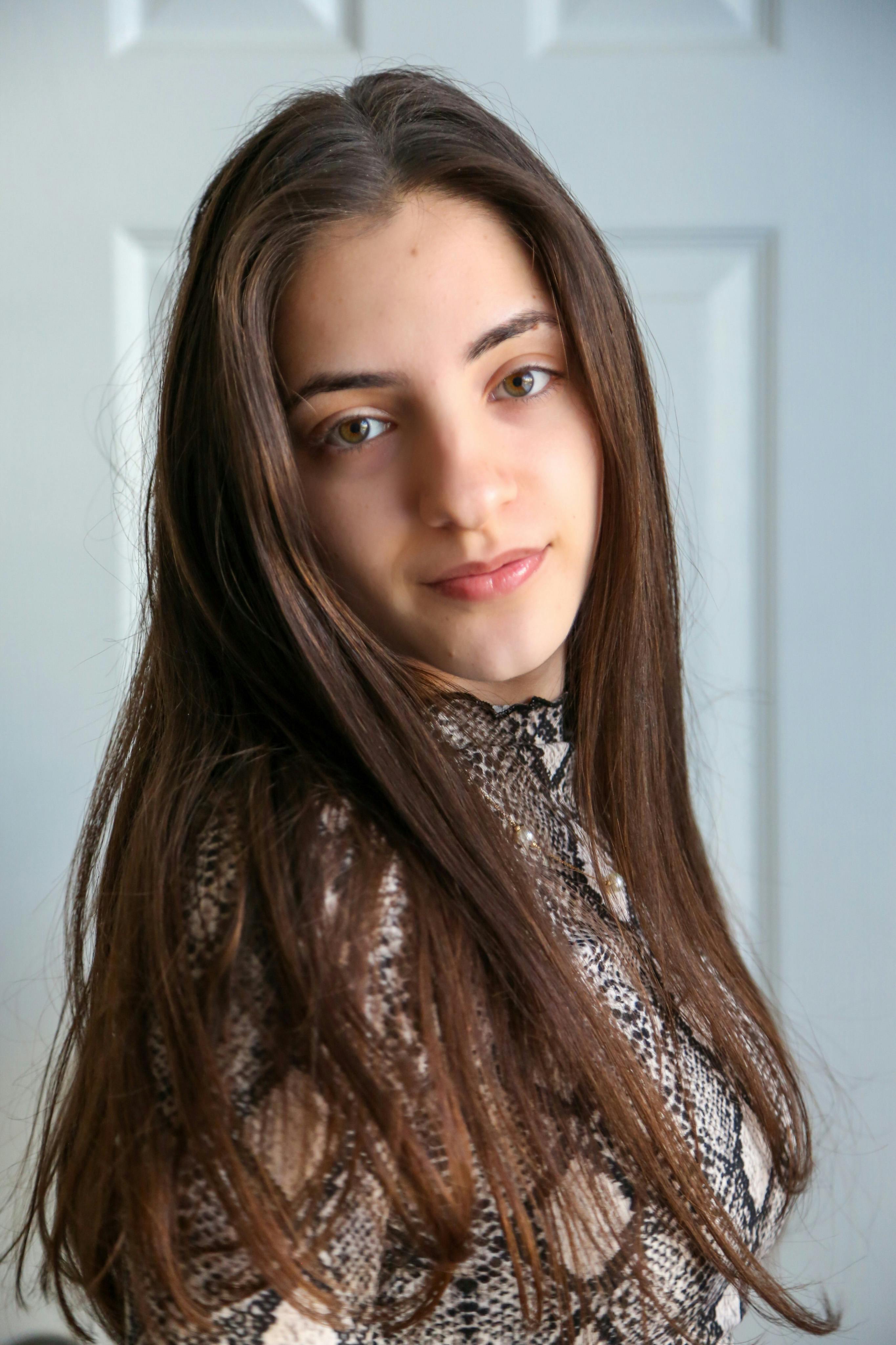 Elegant portrait of a young woman with long hair posing indoors against a door backdrop.