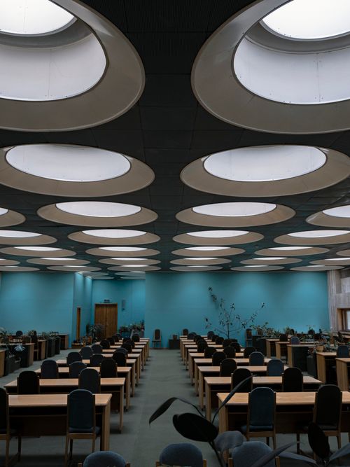 Interior of modern library with geometric ceiling and wooden furniture ...