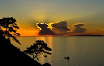 平静的海面上，一艘船的轮廓映衬着绚烂的日落