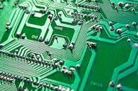 一张绿色电路板的详细视图，可见芯片和路径，突出了技术元素