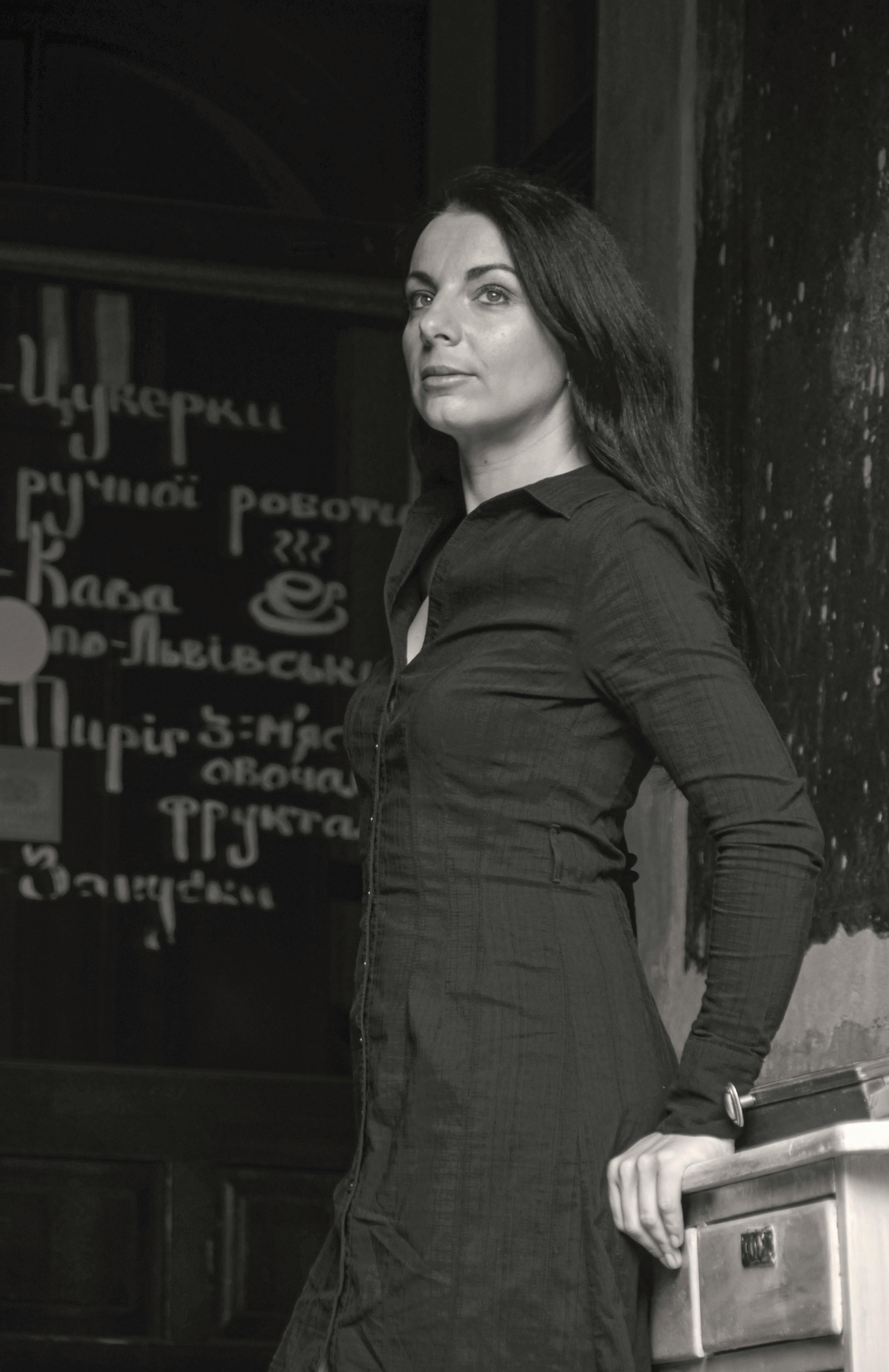 Side view of black and white pensive female in casual clothes leaning on wooden table and looking away