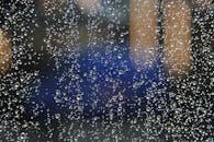 宏观拍摄捕捉到雨滴落在玻璃上，背景模糊