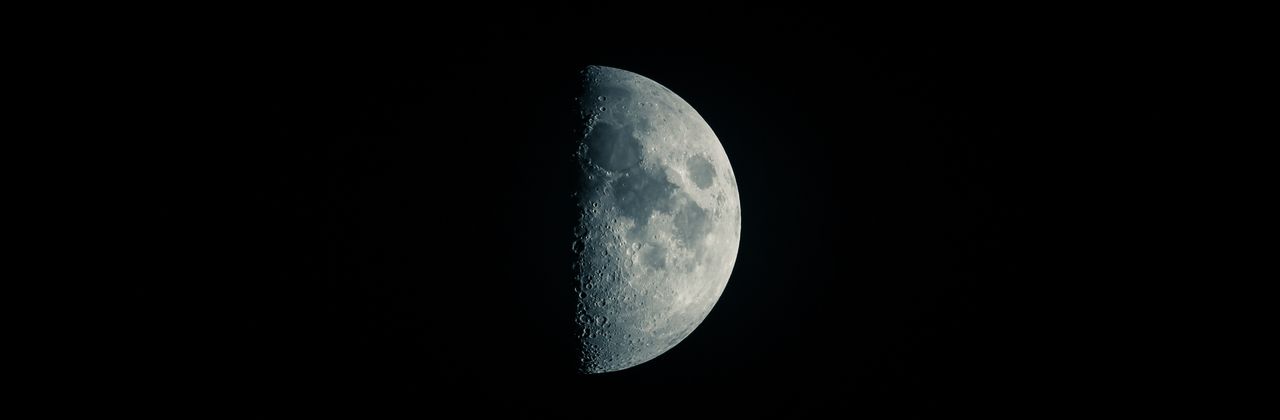 high resolution image of a half moon against a dark sky showcasing lun