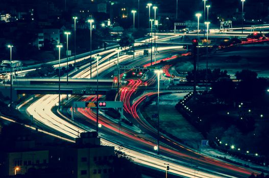 俯瞰夜间城市高速公路，可见动态的光路和繁忙的交通