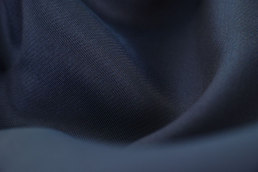 Detailed close-up of woven blue fabric with elegant crumples, highlighting texture and depth.