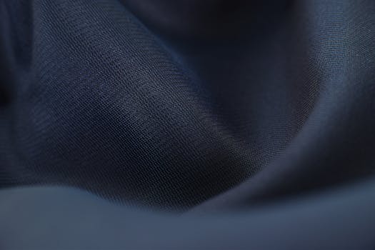 Detailed close-up of woven blue fabric with elegant crumples, highlighting texture and depth.