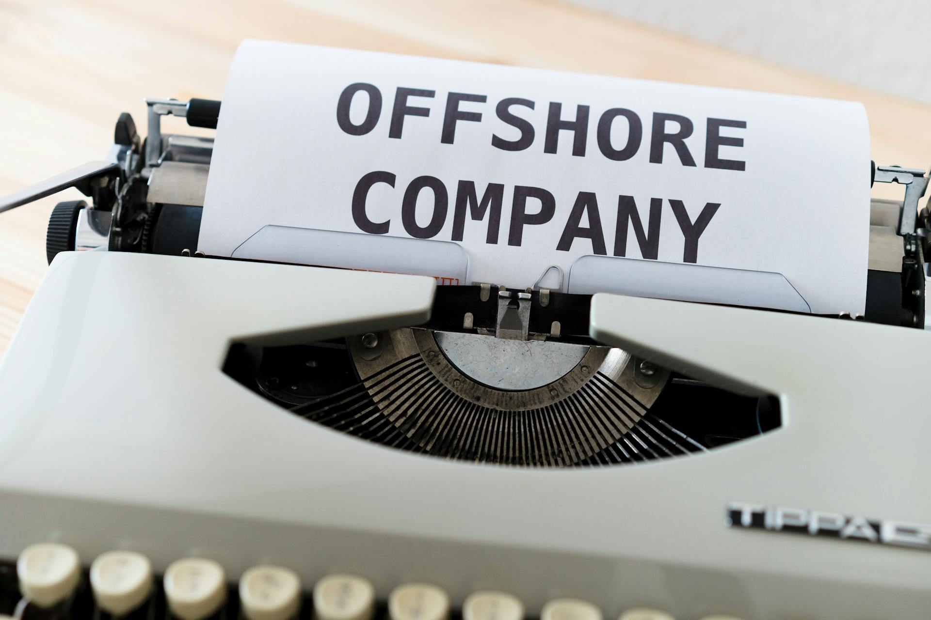 Close-up of a vintage typewriter writing 'Offshore Company' on a paper sheet.