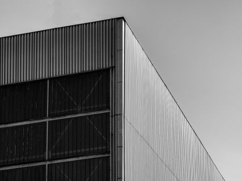 Free A striking black and white photo of a modern industrial building facade showcasing geometric lines. Stock Photo
