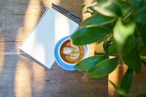 Kostnadsfri bild av anteckningsbok, bord, cappuccino