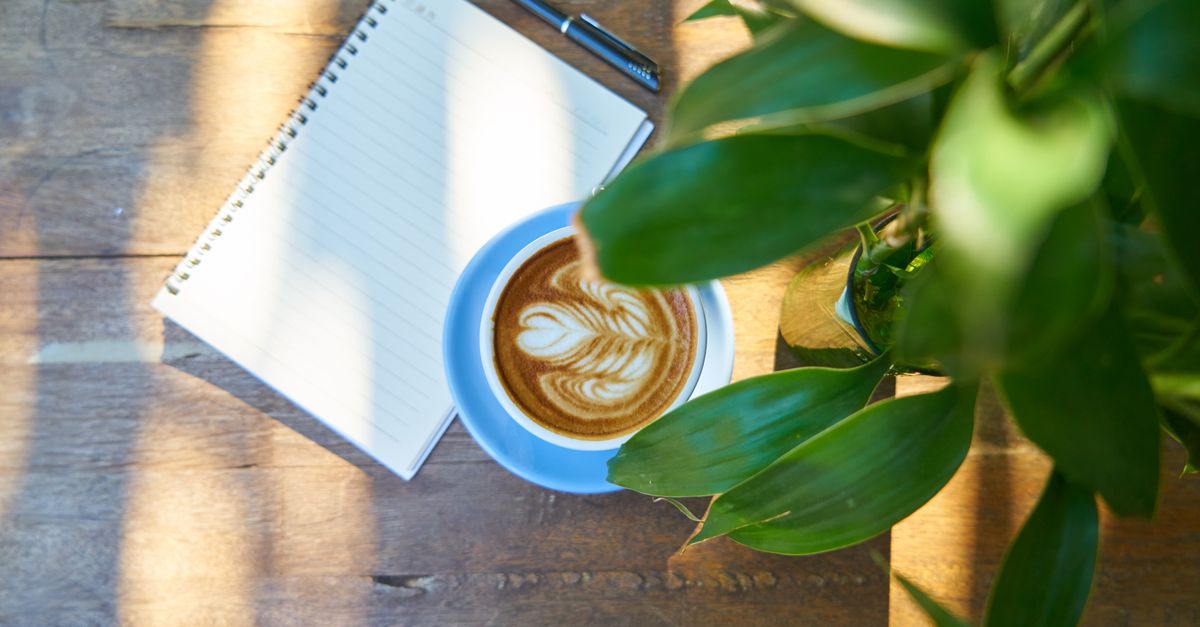 A simple notebook and pen on a wooden table with morning sunlight