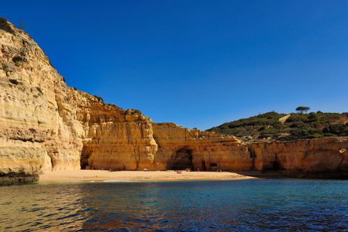 Free Explore the dramatic cliffs and tranquil seashore of Carvoeiro, Algarve under a clear blue sky. Stock Photo