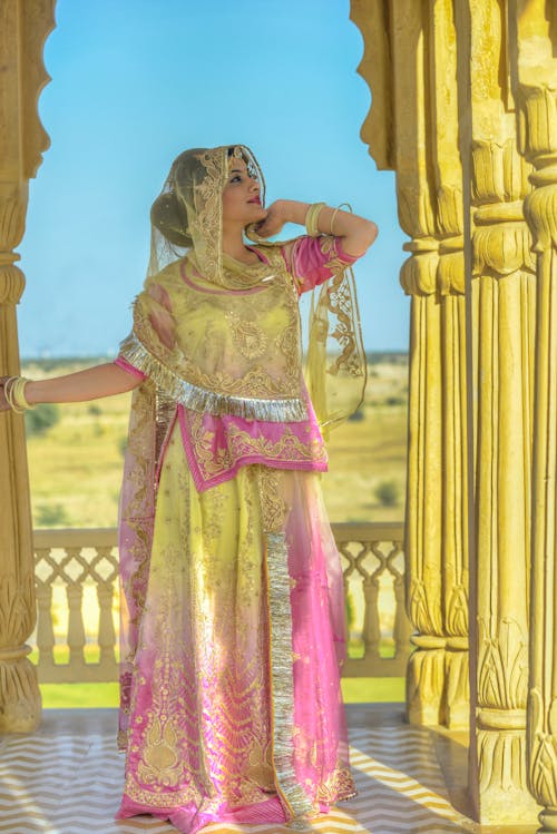 Elegant ethnic lady in sari resting on terrace of Indian palace