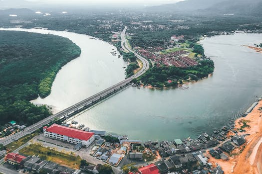 Captivating aerial view of a winding river, bridge, and town nestled in lush greenery.