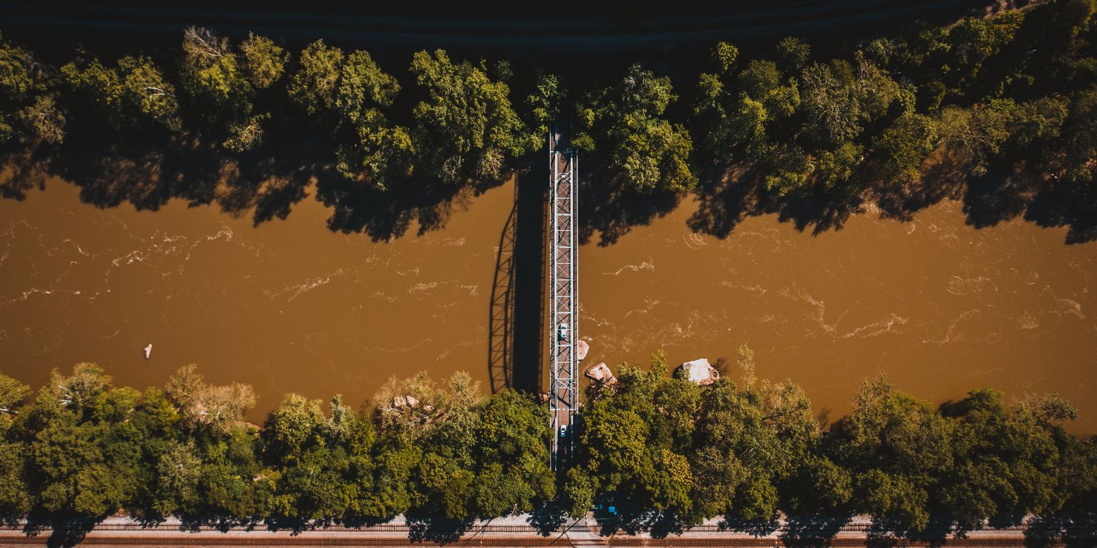 A suspension bridge crossing a river in a green valley