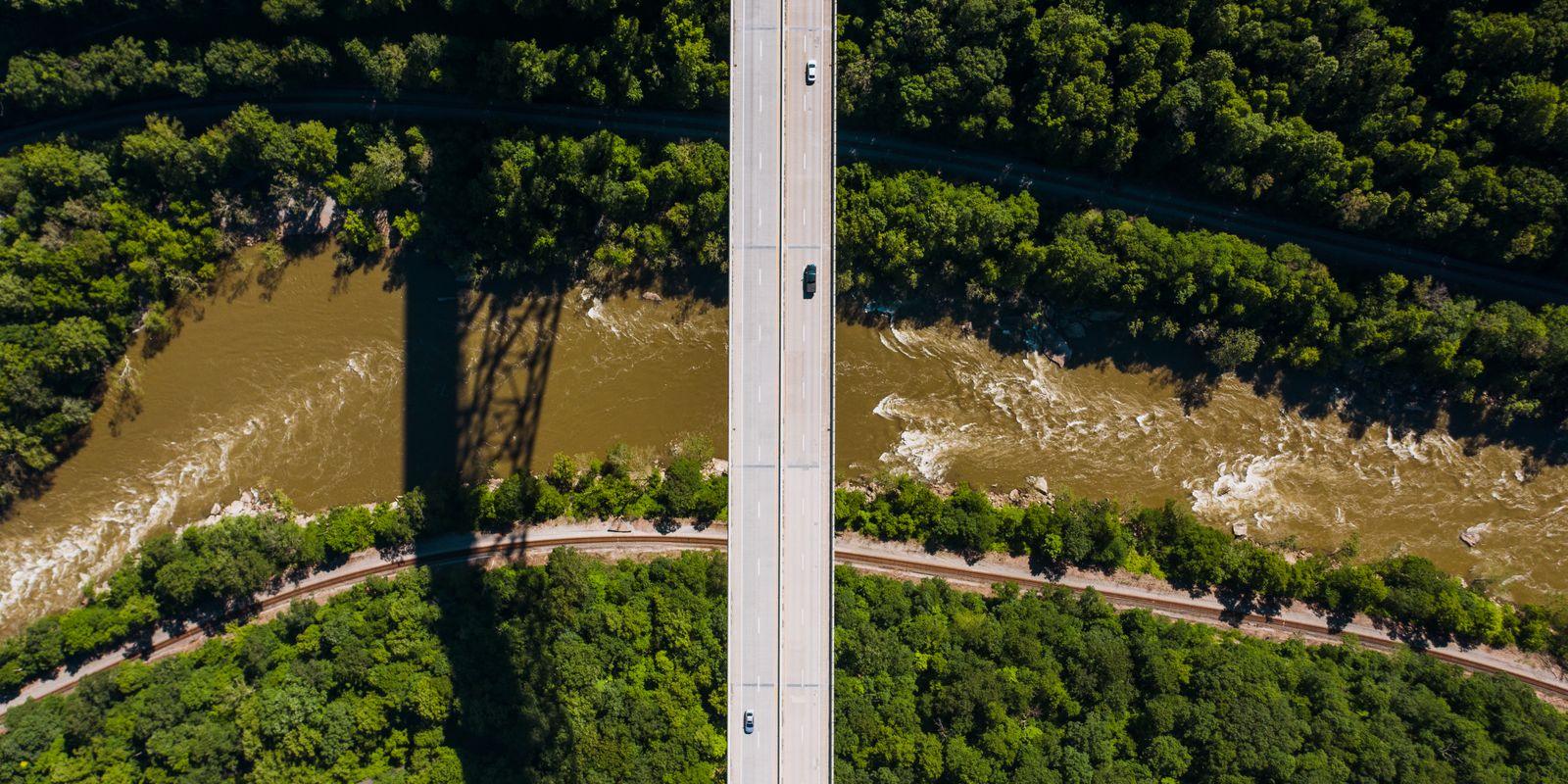 A bridge crossing a river through green forested hills