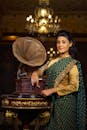 Ethnic woman in traditional dress standing near vintage gramophone