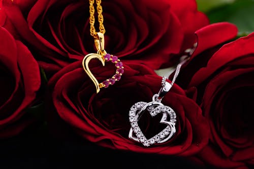 Silver and gold decorative hearts with small gems placed on bud of red rose