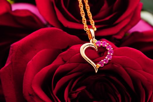 Bunch of bright red roses with golden accessory with pink gems placed above
