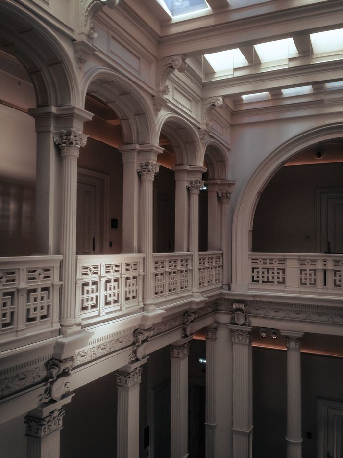 Skylit gallery with white arches and carved balustrades, by taha balta on Pexels