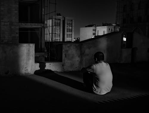 Free Lonely man sitting on rooftop at night Stock Photo