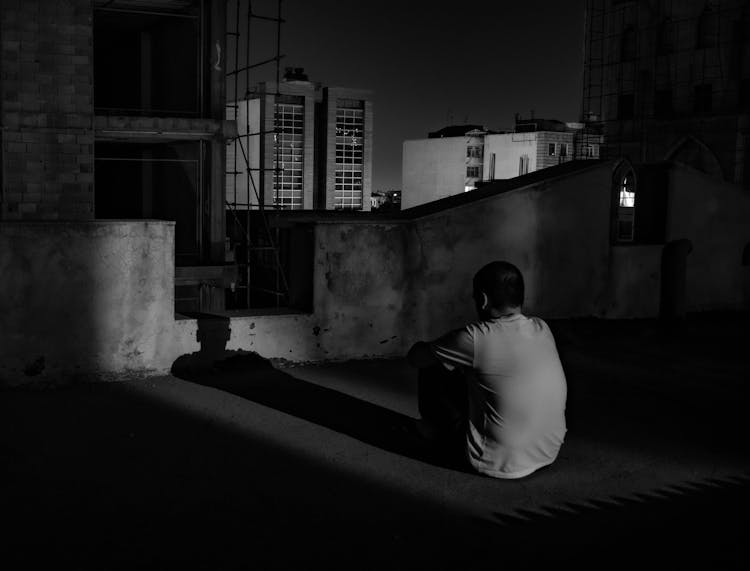 Lonely Man Sitting On Rooftop At Night