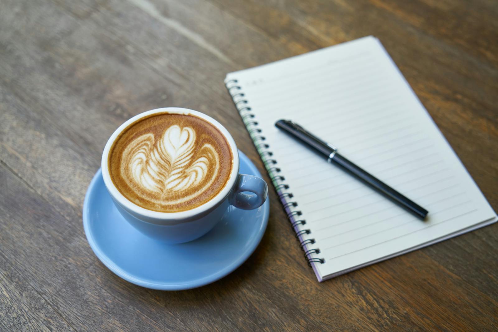 Latte art next to a notebook for planning a coffee tour