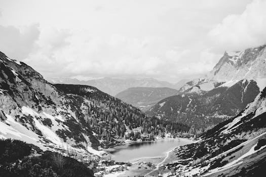Stunning black and white image of a snowy mountain valley with a serene lake.