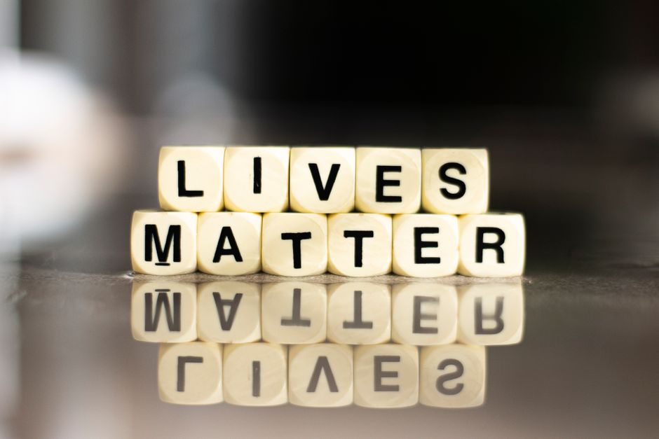 Cubes spelling out 'Lives Matter' with reflection on a smooth surface.