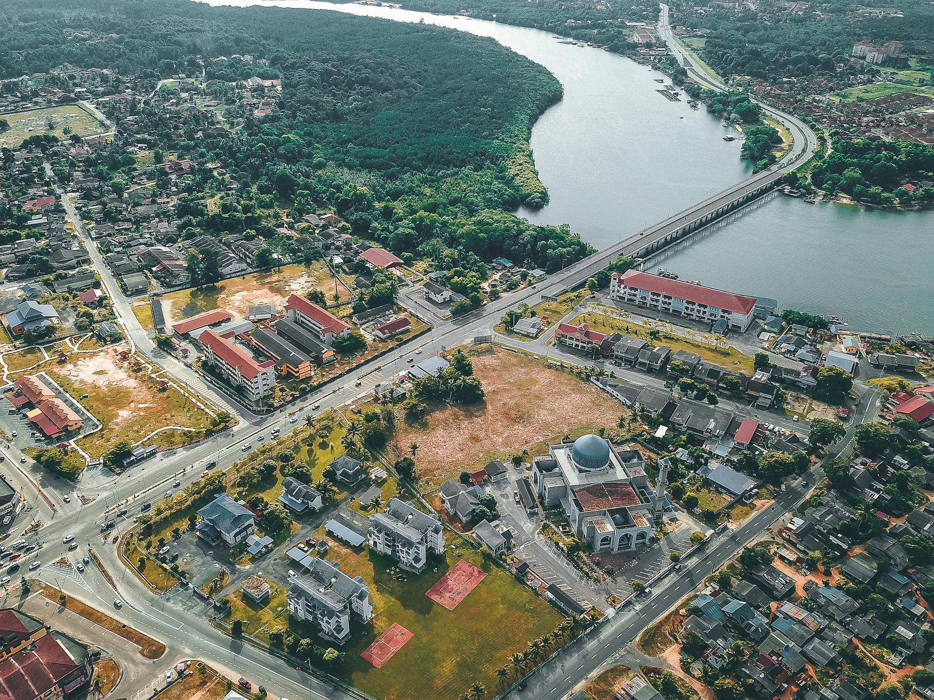 Aerial photograph capturing a vibrant riverfront urban area with a bridge spanning over a river, showcasing residential and commercial buildings.