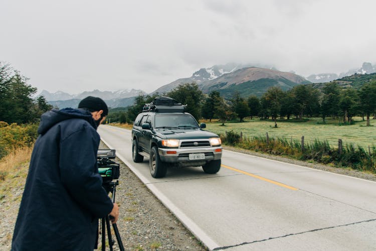 Photographer Taking Photo Of Car On Road