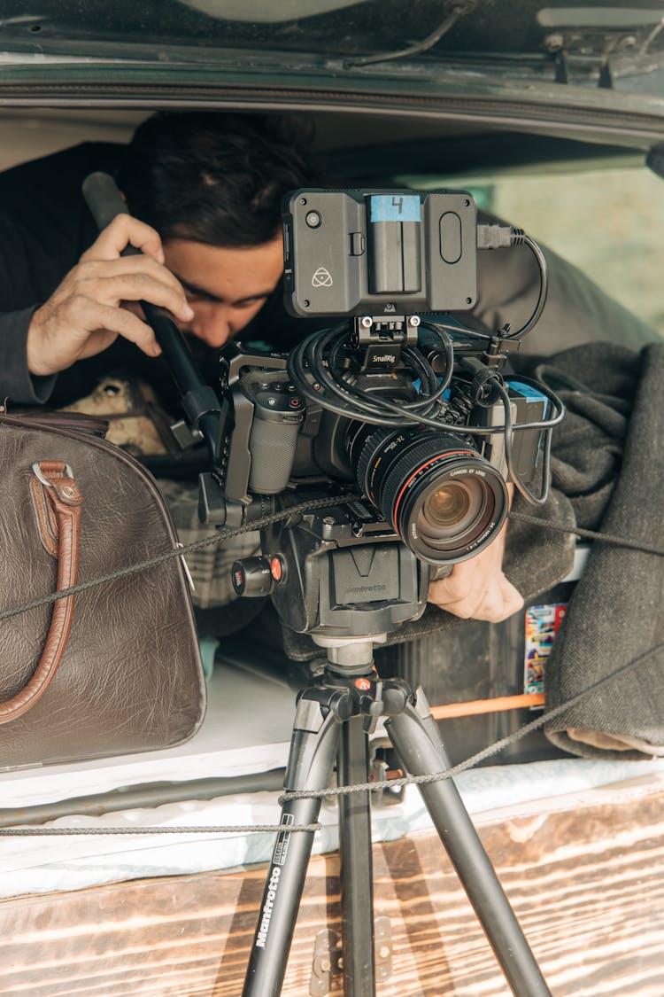 A Man Setting Up His Black Camera