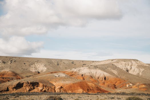 Stunning view of Argentina's desert terrain with red dunes and a dramatic cloudy sky.