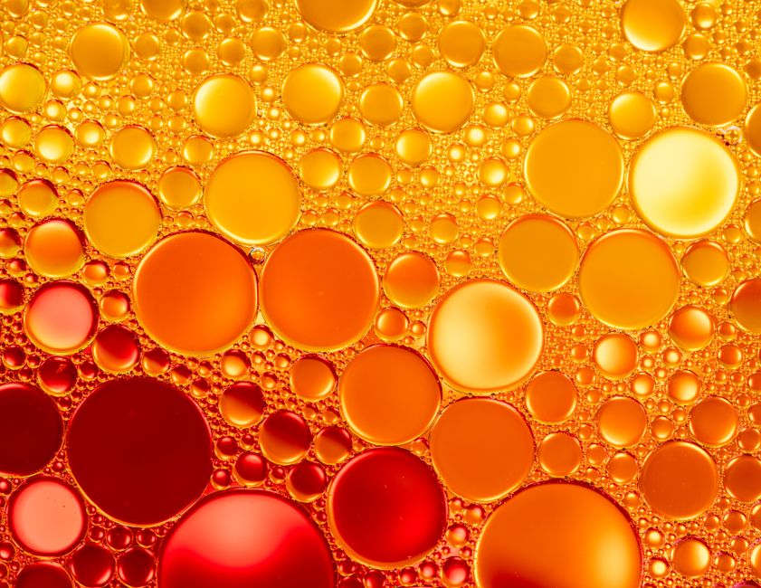 From above of vibrant glistening red and orange rings on colorful liquid surface in light of lamps