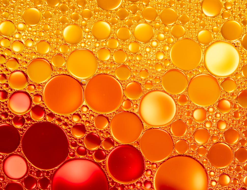 Free From above of vibrant glistening red and orange rings on colorful liquid surface in light of lamps Stock Photo
